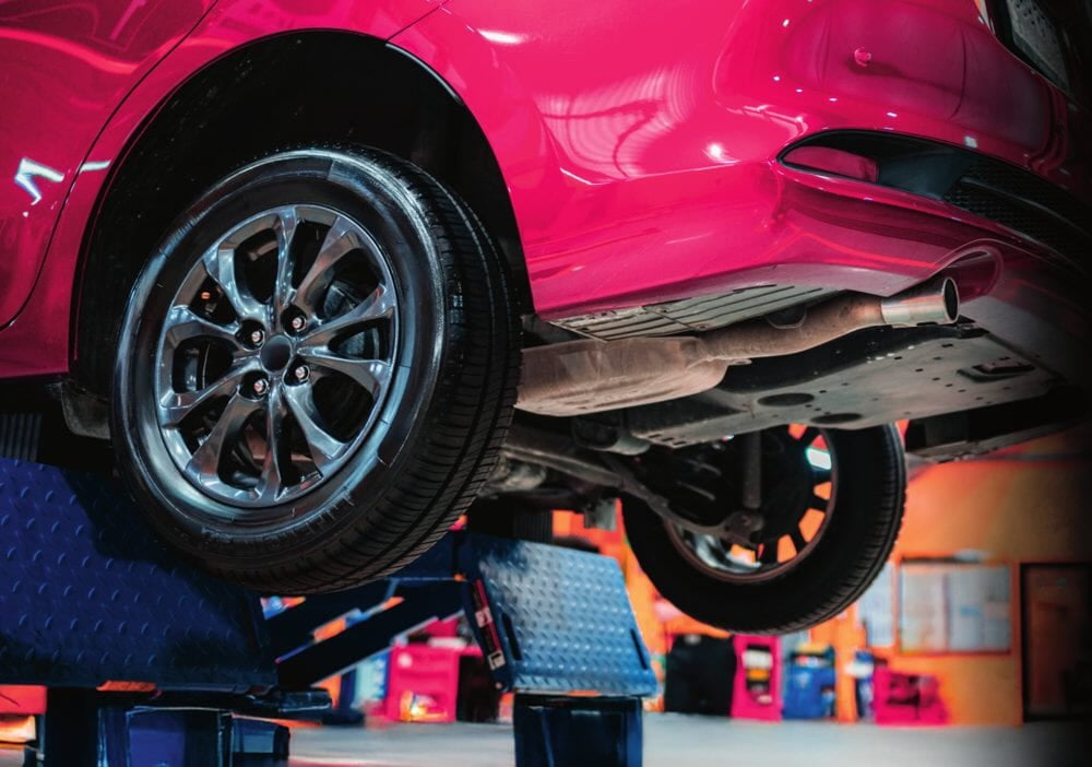 Car raised on an automotive lift in a service bay